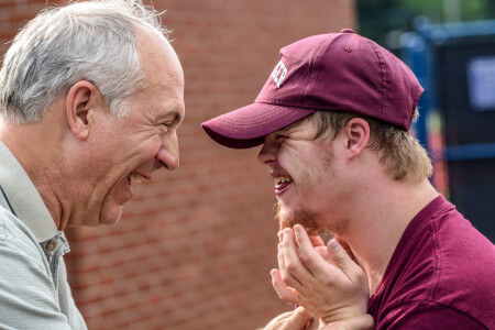 A man with Down syndrome and another man smiling