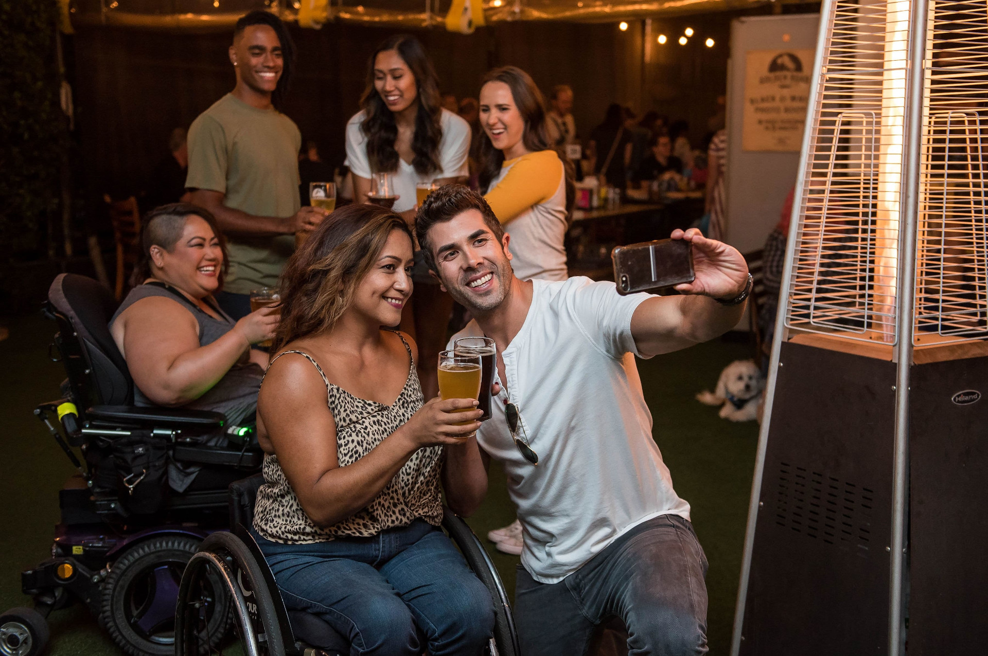 Two wheelchair users share drinks with other people