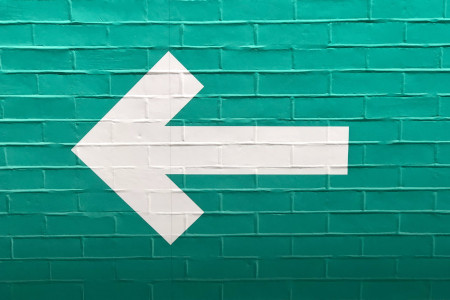 A white arrow pointing left on a green wall