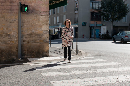 A blind woman is crossing the street in France after actuating the accessible pedestrian signals with her remote control
