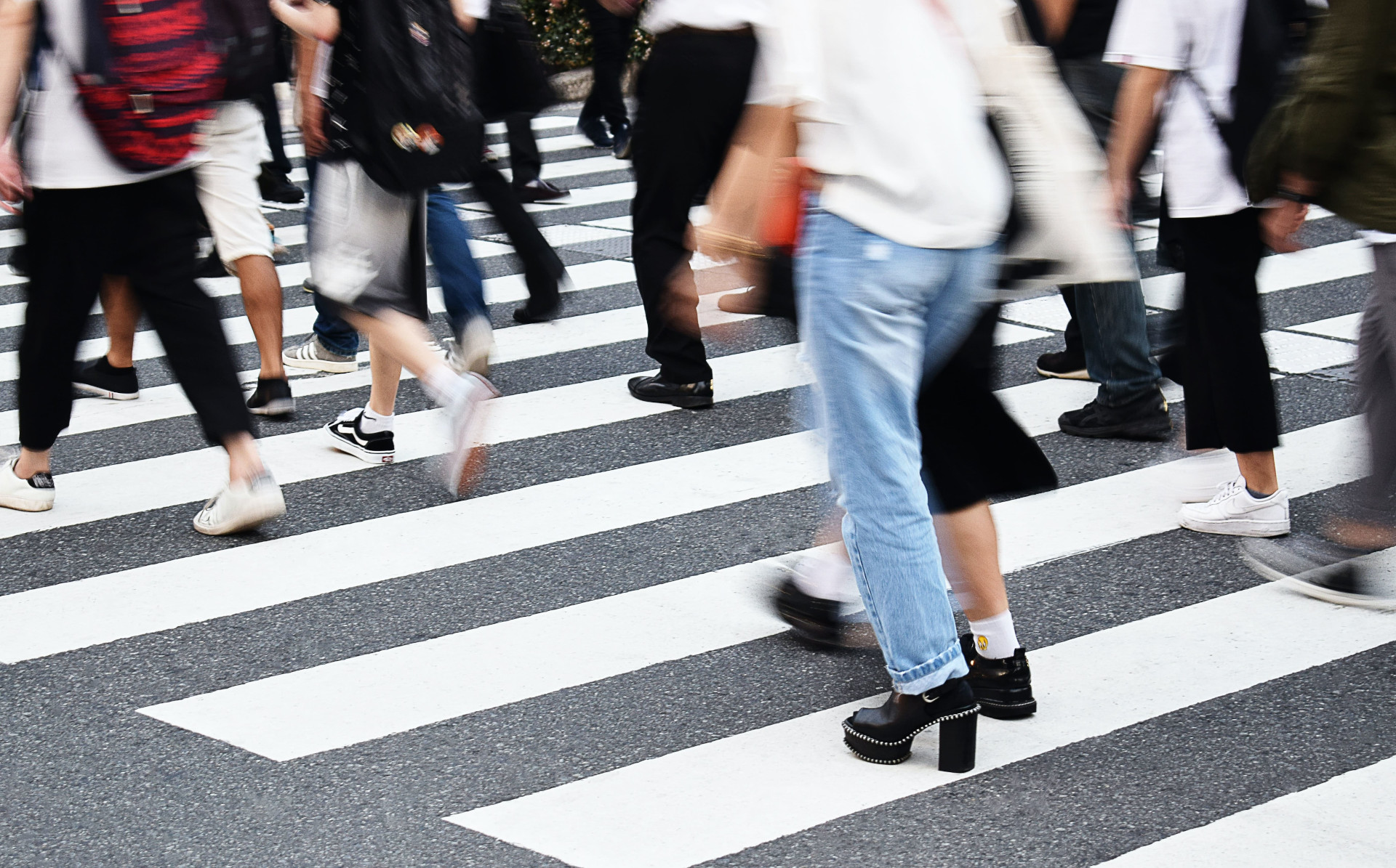 A crosswalk with black and white stripes used by a lot of pedestrians
